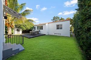 einen Hinterhof mit einem weißen Haus mit einem Rasenplatz in der Unterkunft Miami Art Deco Home By Pmi in Miami