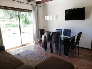 a dining room with a table and chairs and a television at Cabañas Am Berg in Pucón