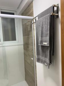 uma casa de banho com uma cabina de duche em vidro e toalhas em Recanto Terraneo-Gramado em Gramado