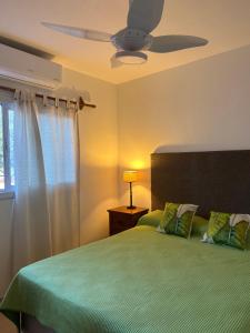 1 dormitorio con 1 cama verde y ventilador de techo en Aires del cerro en Salta