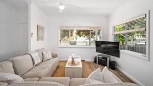 Una sala de estar con un sofá y un televisor de pantalla plana. en Harrys Pet Friendly Holiday House, en Nelson Bay