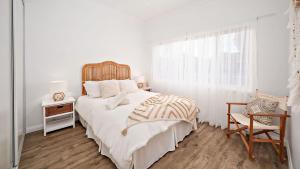 Un dormitorio blanco con una cama grande y una silla. en Harrys Pet Friendly Holiday House, en Nelson Bay