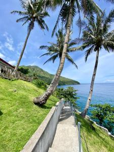a path leading down to the ocean with palm trees at Tongatok Cliff Resort in Mambajao