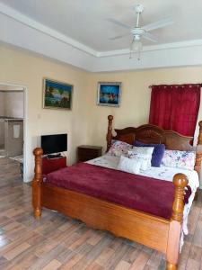 1 dormitorio con cama de madera y cortina roja en Alluring 1 Bedroom Penthouse Suite/ Priv. Terrace, en Kingston