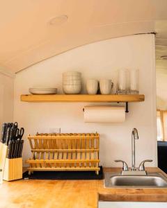 una cocina con fregadero y un estante con platos en Serene Bus Getaway Among Rolling Farm Land en Granville
