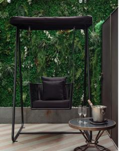 a black swing with a table in front of a green wall at Naumi Hotel in Singapore