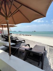 a group of chairs and an umbrella on the beach at LANTA PURA beach resort-SHA extra plus in Ko Lanta