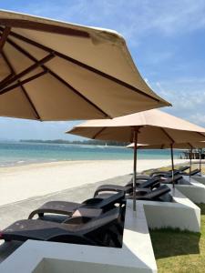 a group of chairs and an umbrella on the beach at LANTA PURA beach resort-SHA extra plus in Ko Lanta