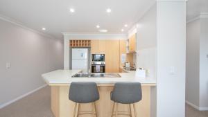a kitchen with two stools at a kitchen island at The Sands Resort at Yamba in Yamba