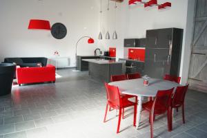 une cuisine avec une table blanche et des chaises rouges dans l'établissement GrIsa'Home, à Aisonville-et-Bernoville