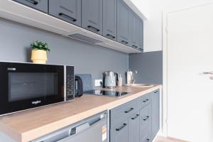 a kitchen with white cabinets and a black microwave at Posti Guesthouse in Rakvere