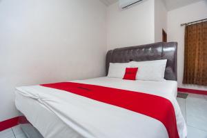 una camera da letto con un grande letto con una coperta rossa di RedDoorz Syariah near Tugu Juang Jambi 3 a Jambi