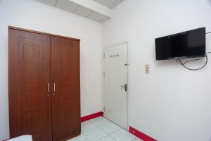 um quarto com um armário e uma televisão na parede em RedDoorz Syariah near Tugu Juang Jambi 3 em Jambi