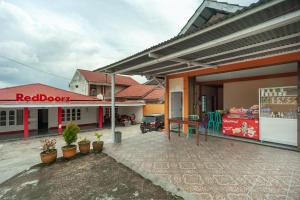 um edifício com uma porta vermelha e uma loja em RedDoorz Syariah near Tugu Juang Jambi 3 em Jambi