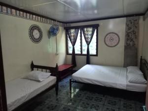 two beds in a room with two windows at WAI MAKARE HOMESTAY ROOM 2 in Naviti Island