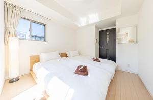 a bedroom with a white bed with a brown purse on it at SQUARE渋谷312 in Tokyo
