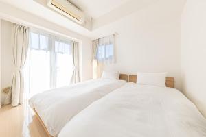 a white bedroom with two beds and a window at SQUARE渋谷312 in Tokyo