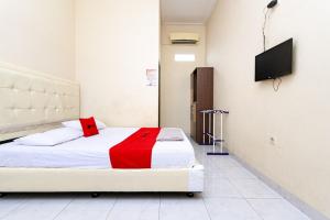 a bedroom with a bed with a red blanket at RedDoorz @ Jalan Sidomuncul 2 Jambi in Jambi