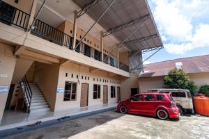 a red car parked in front of a building at RedDoorz @ Jalan Sidomuncul 2 Jambi in Jambi