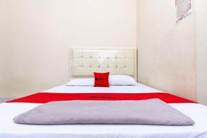 Una cama blanca con una almohada roja. en RedDoorz @ Jalan Sidomuncul 2 Jambi en Jambi