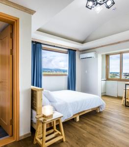 - une chambre avec un lit et une grande fenêtre dans l'établissement Romance Jeju Pension, à Jeju