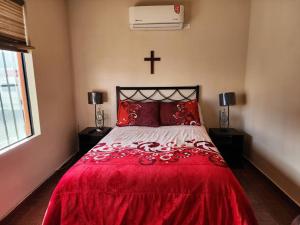 a bedroom with a red bed with a cross on the wall at Departamento en planta baja en centro de Cananea in Cananea