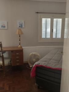 1 dormitorio con cama, escritorio y ventana en Casa Mariclaire en Bahía Blanca