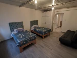 Habitación con 2 camas y sofá en Suite Doble en Parque la Carolina, en Quito