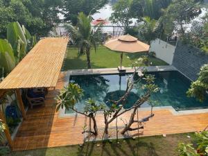 einen Pool mit einer Holzterrasse und einem Sonnenschirm in der Unterkunft TROPICAL HOUSE RIVERSIDE RETREAT in Thuan An