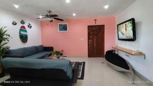 a living room with a blue couch and a pink wall at Casa Gacela Cozumel in Cozumel