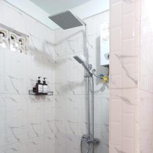 y baño con ducha y azulejos blancos. en Toraja Homestay & Coffee Bunna, en Rantepao
