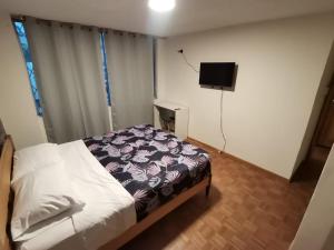 1 dormitorio con 1 cama y TV de pantalla plana en Dormitorio Amplio cerca de Parque Carolina, en Quito