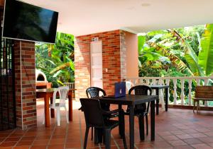 d'une terrasse avec des tables et des chaises et une télévision. dans l'établissement Finca Hotel Villa Gladys en Mesitas del Colegio, à El Colegio