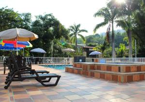 um pátio com cadeiras e guarda-sóis e uma piscina em Finca Hotel Villa Gladys en Mesitas del Colegio em El Colegio