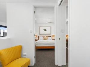 a bedroom with a bed and a yellow chair at 1 Bedroom Modern Townhouse in Casuarina in Casuarina
