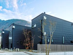un bâtiment noir avec des montagnes en arrière-plan dans l'établissement Rakuten STAY HOUSE x WILL STYLE Yufuin Kawakami 101, à Yufu