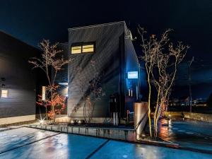 un edificio di notte con alberi di fronte di Rakuten STAY HOUSE x WILL STYLE Yufuin Kawakami 101 a Yufu