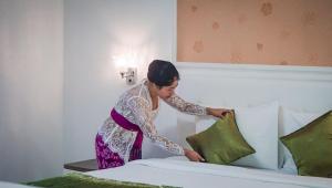 a woman putting a pillow on top of a bed at Kesari Penida by Mahaprana Home in Nusa Penida