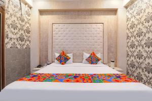 a bedroom with a large white bed with colorful sheets at FabHotel Triveni in Jahāngīrābād