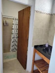 baño con lavabo y puerta de madera en Complejo Monaco Calamuchita en Santa Rosa de Calamuchita
