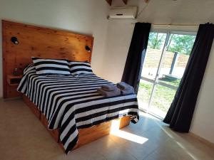 una camera con letto con testiera in legno e finestra di Complejo Monaco Calamuchita a Santa Rosa de Calamuchita