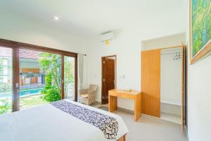um quarto com uma cama, uma secretária e uma janela em Kubu Mesari Homestay by Bukit Vista em Canggu
