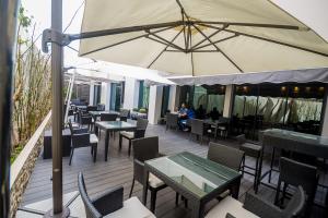 eine Terrasse mit Tischen und Stühlen und einem Sonnenschirm in der Unterkunft Rysara Hotel in Dakar