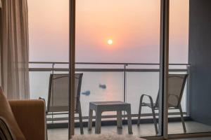 a balcony with two chairs and a table and a sunset at Veranda Pattaya/3BR Seaview/32FL in Jomtien Beach