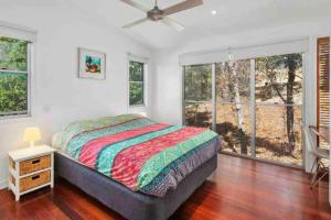 1 dormitorio con 1 cama y ventanas grandes en Treetops on Tramican - Ocean View - sleeps 10, en Point Lookout