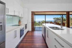 波因特卢考特Treetops on Tramican - Ocean View - sleeps 10的一间厨房,配有白色的橱柜,享有海景