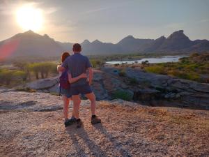 a man and woman standing on top of a mountain watching the sunset at Jawai Bagpackers Hostel in Sheoganj
