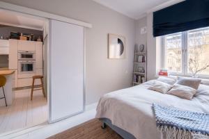 a white bedroom with a large bed and a kitchen at Elegant city home two blocks from Senate Square. in Helsinki