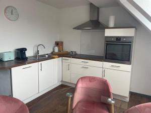 a kitchen with white cabinets and a red chair at Gemütliche Stadtwohnung “Elmrand“ mit Stadtblick in Schöppenstedt
