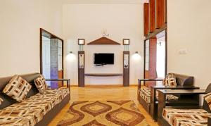 a living room with two couches and a tv at Itsy By Treebo - Twin Falls in Ooty